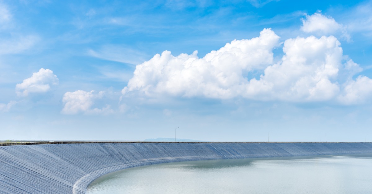 A large artificial lake is partially filled with water and has a black liner covering the sides.